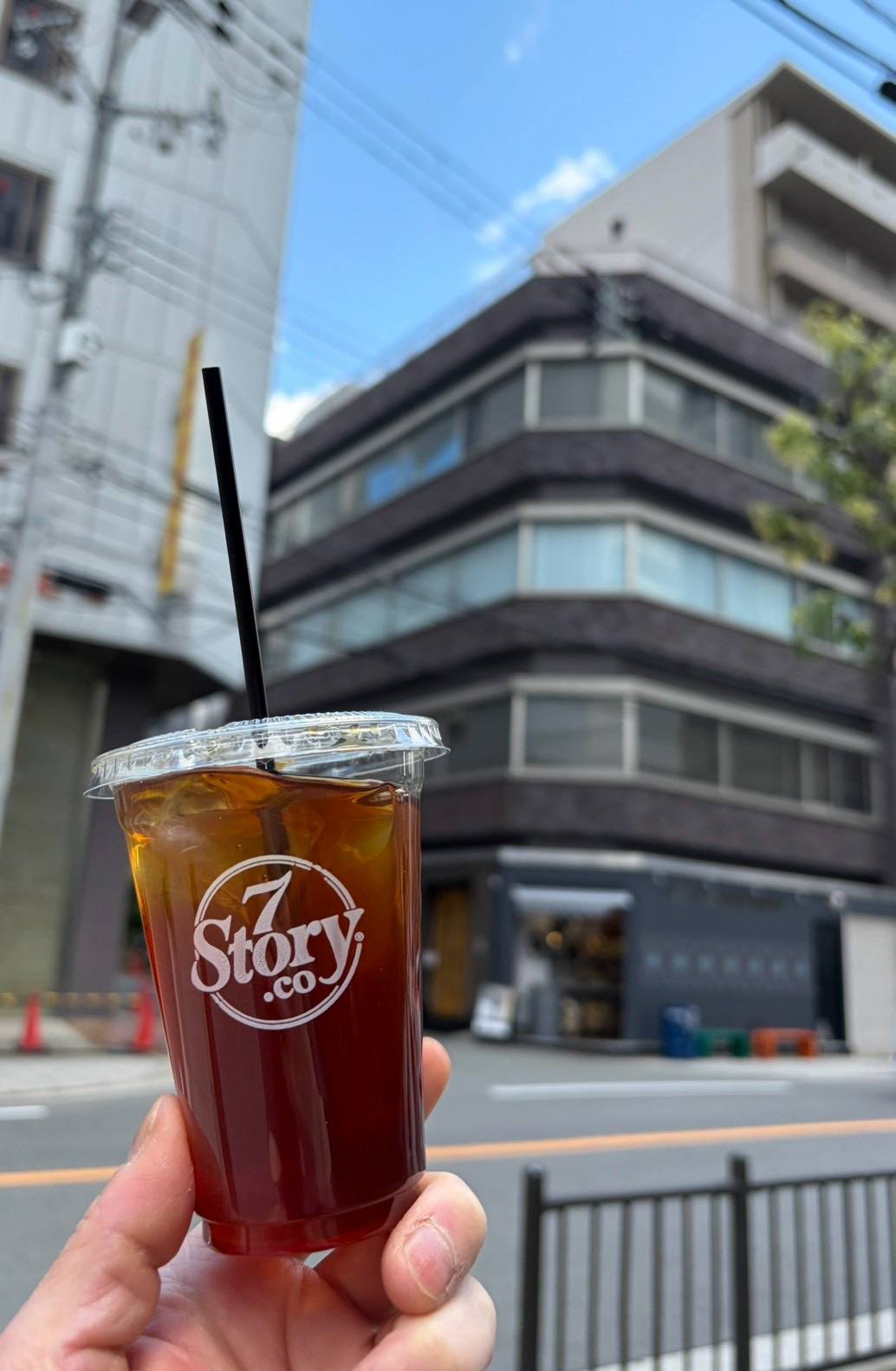 店舗を背景に掲げたテイクアウトのアイスコーヒー